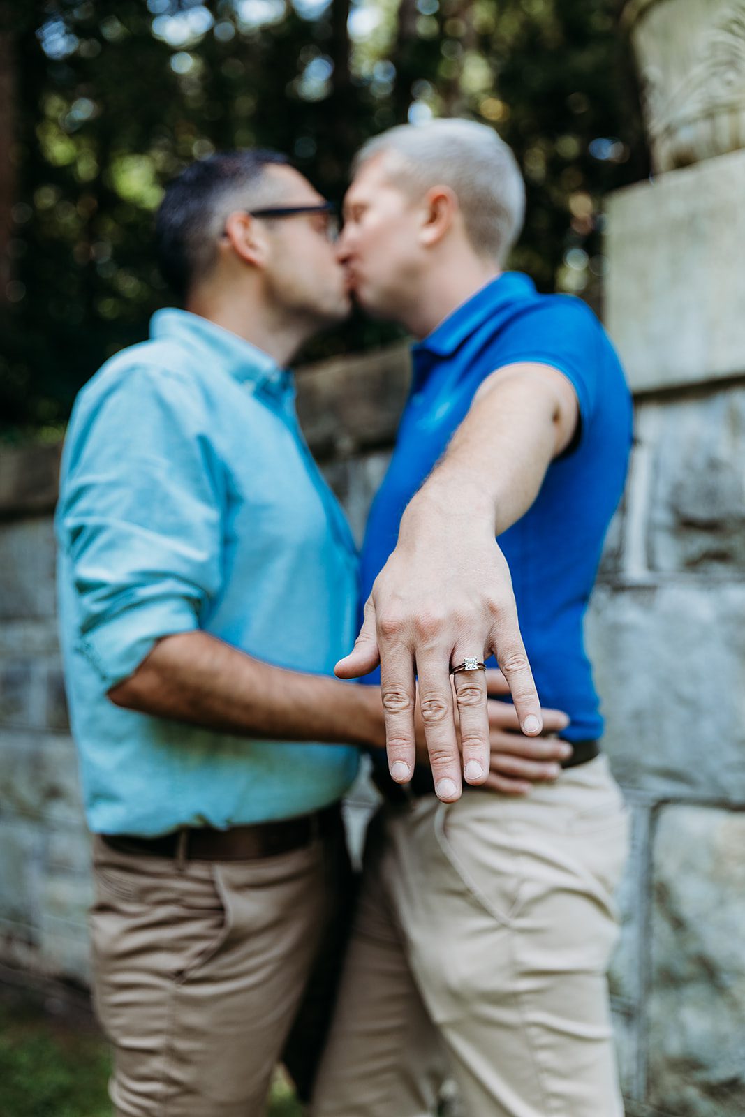 Details of an engagement ring being showed off by a man as he kisses his fiancee in the Yaddo Gardens wedding venue