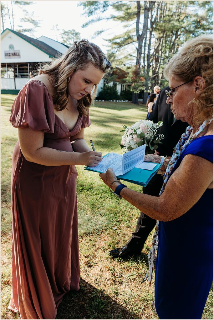 A bridesmaid signs a New York State marriage license.
