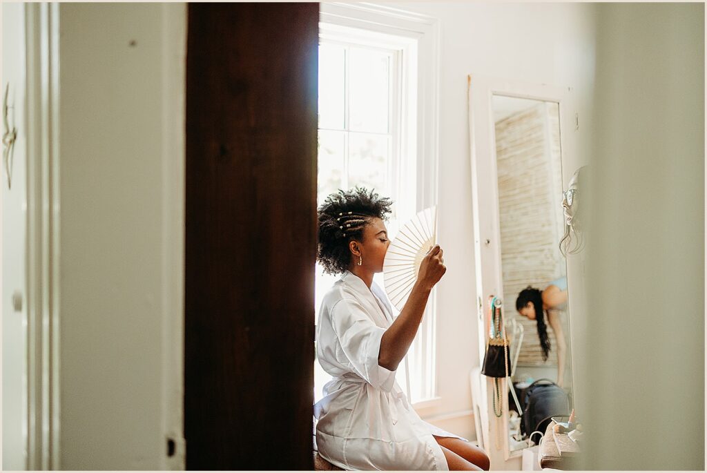 A bride fans herself in a getting ready suite.