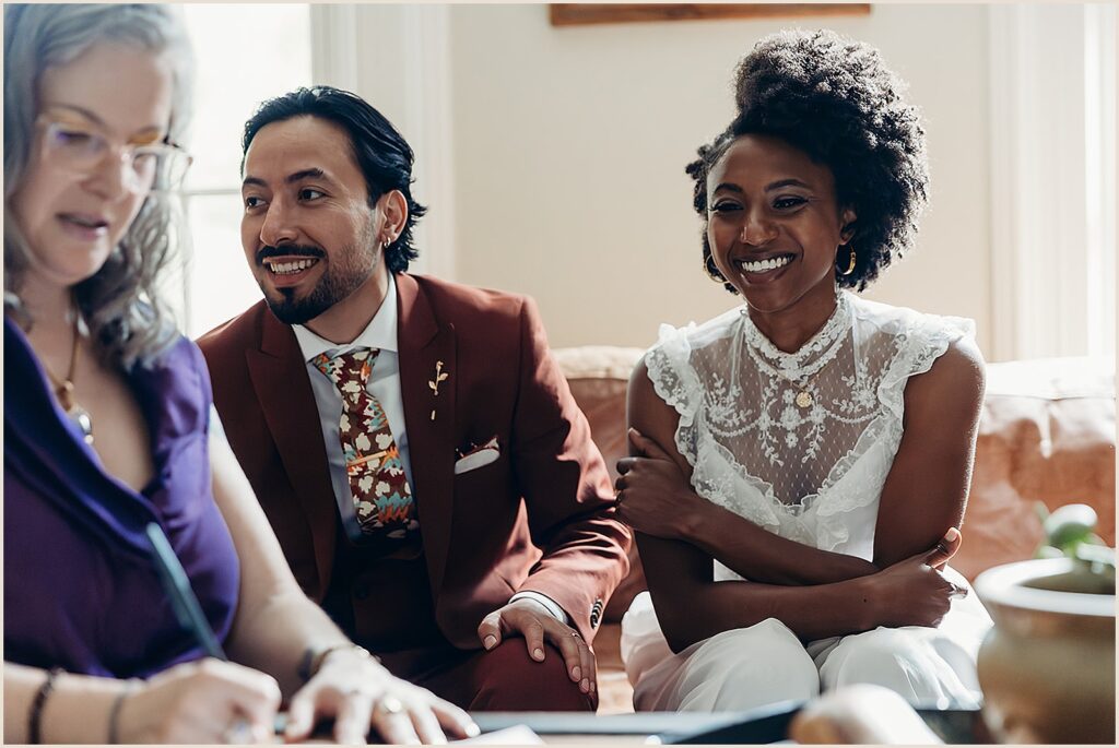 A bride and groom watch a witness sign their New York State marriage license.