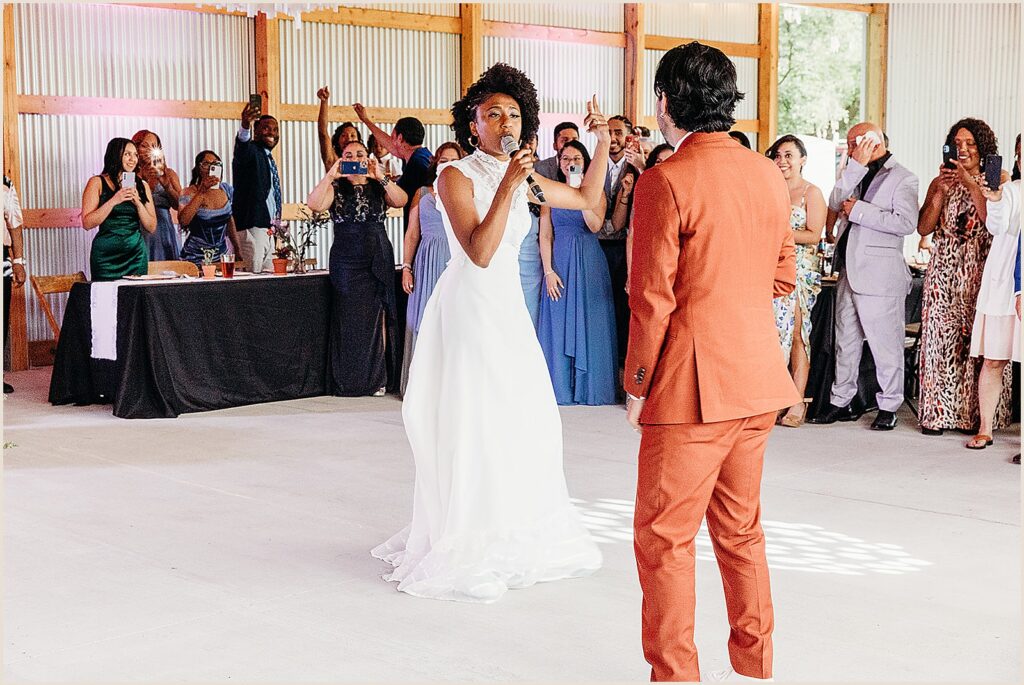 A bride sings to a groom at a wedding reception.