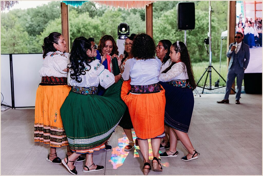 Women in traditional Ecuadorian dresses dance in a circle.