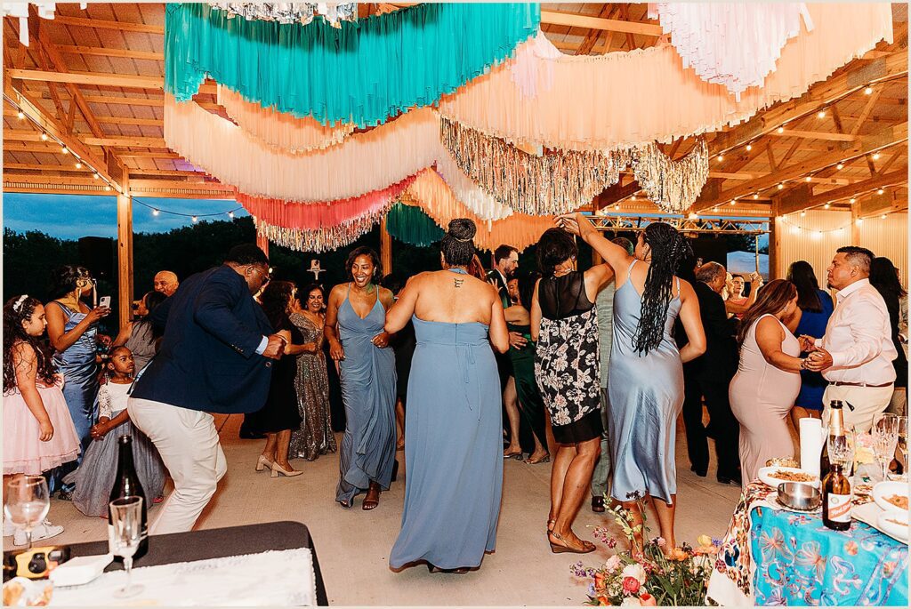 Bridesmaids dance beneath a fringe installation.