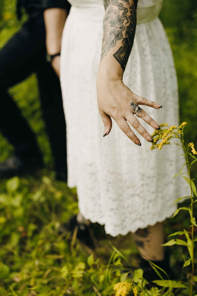 A bride and groom walk through a field of wildflowers.