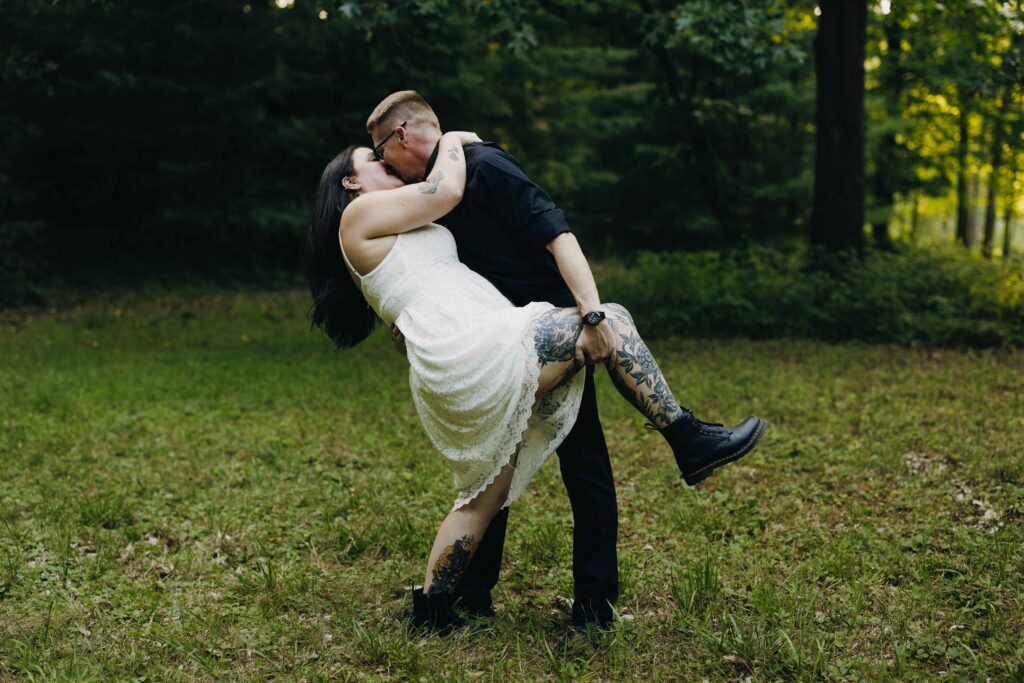 A groom dips a bride for a kiss at their Adirondacks elopement.