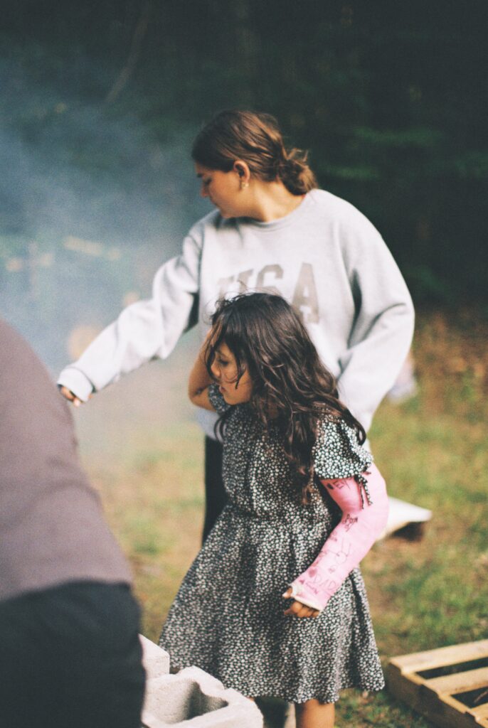 Two people watch a man roasting a pig.