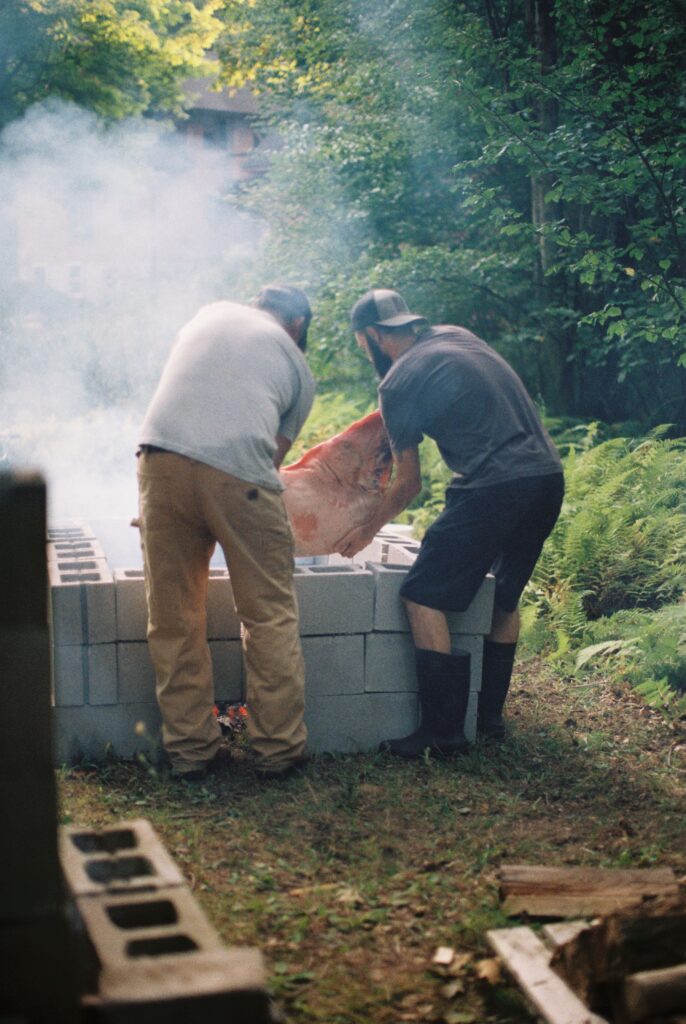 Smoke rises beside a roasting pit.