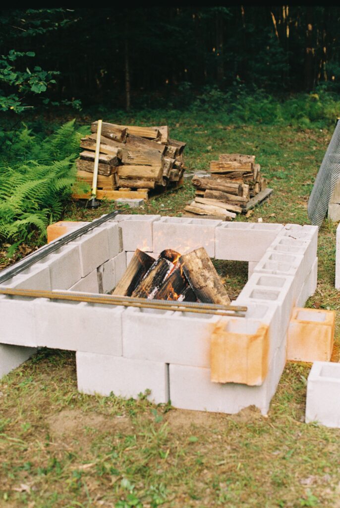A stack of logs sit in a pit before a roast.