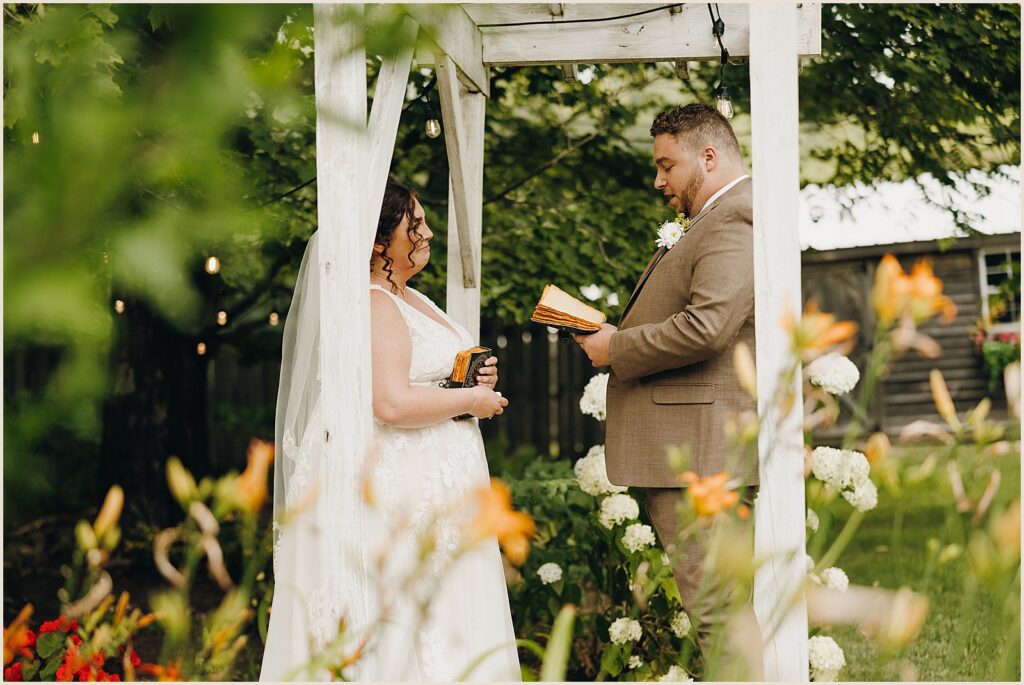 A bride and groom exchange private vows under an arbor at Greywacke Meadows.