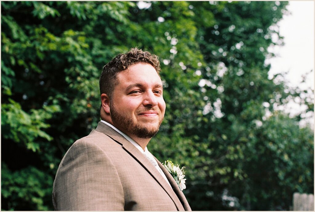 A groom smiles in a film wedding photo.