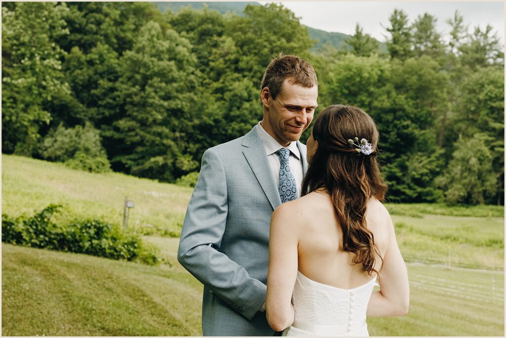 A groom smiles at a bride during their first look at a Vermont wedding.