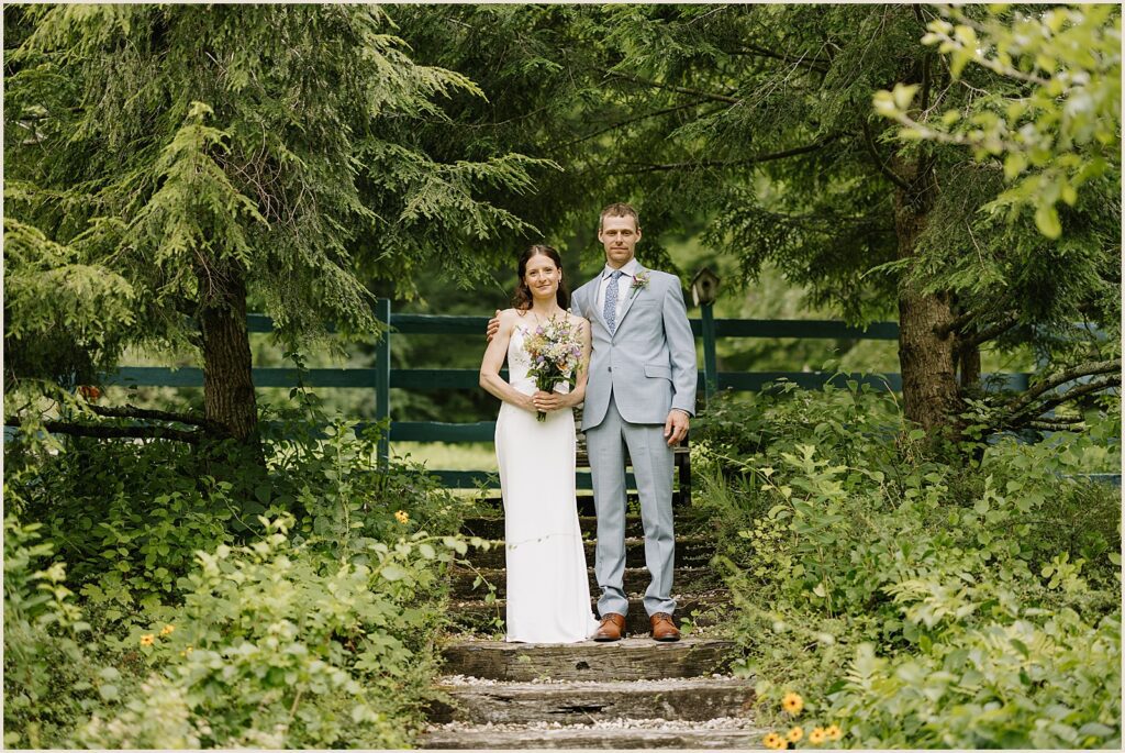 A bride and groom pose side by side in front of a fence at a West Mountain Inn wedding.