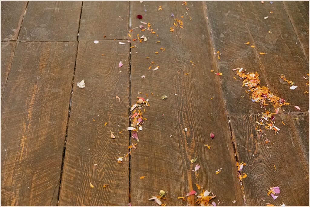 Flower petals lay on the wooden floor of a Vermont wedding venue.