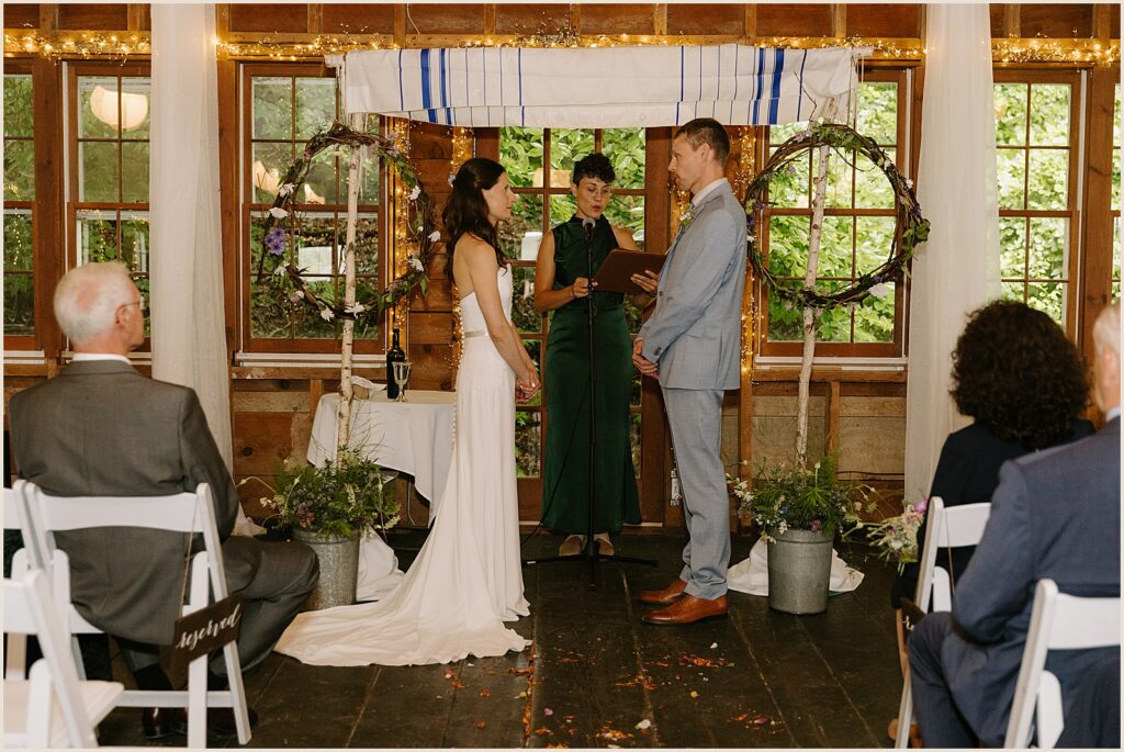 A bride and groom stand under a chuppah inside the West Mountain Inn.