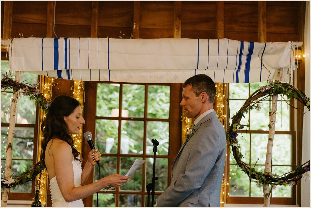 A bride reads her vows into a microphone.