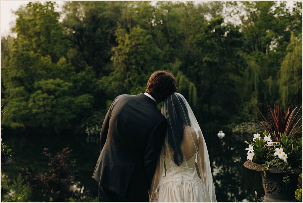 A bride and groom look out over the pond at Windrift Hall.